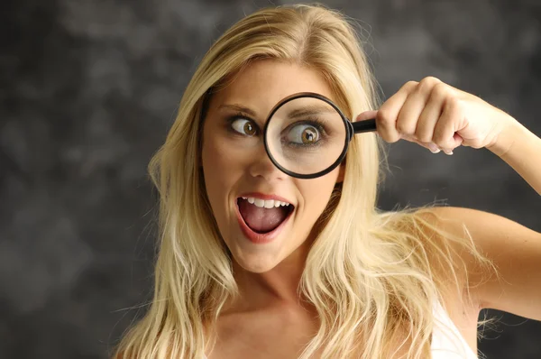 Blonde girl with a magnifying glass — Stock Photo, Image