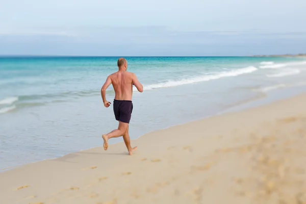 Чоловік біжить на пляжі — стокове фото