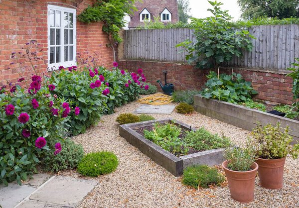 English cottage garden with gravel, UK. York stone paving and oak sleeper raised beds 