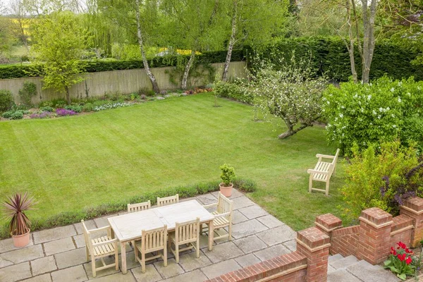 Garden patio with furniture on a terrace in a UK landscaped back garden with large lawn