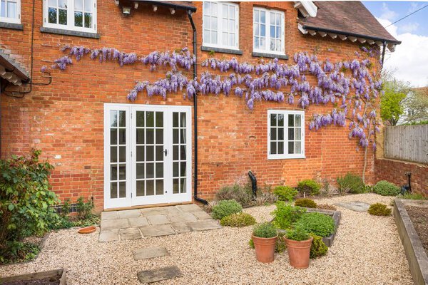 Викторианский дом с деревянными окнами, французскими дверями и вистерией. Гард ландшафтный сад с Йоркским каменным патио и Февел. Англия, Великобритания