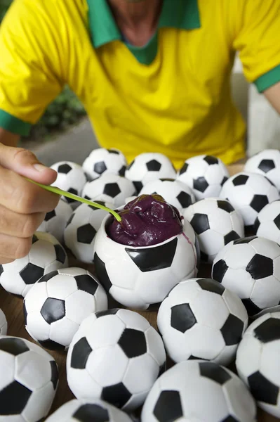 Brasiliansk fotbollspelare äter acai med fotbollar — Stockfoto