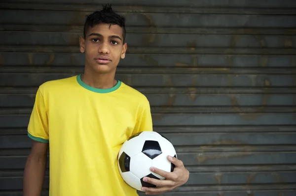 Молодой бразильский футболист проводит футбол — стоковое фото