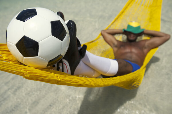 Brazilian Soccer Player Relaxes with Football in Beach Hammock