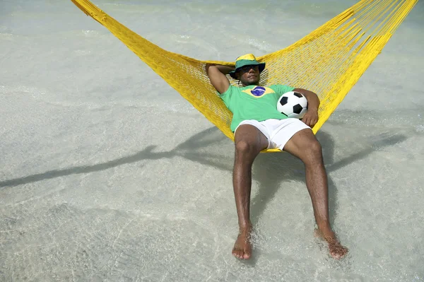 Uomo brasiliano rilassante con calcio calcio in amaca da spiaggia — Foto Stock