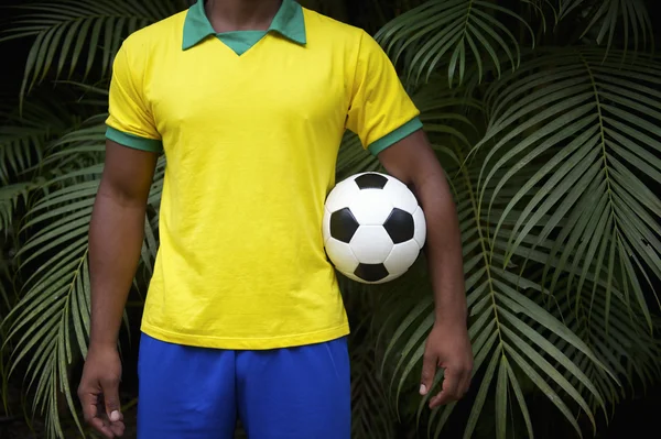 Joueur de football brésilien tenant un ballon de football dans la jungle — Photo
