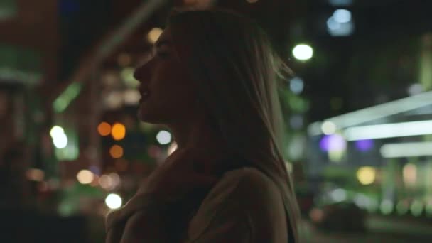 Όμορφη νεαρή κοπέλα ξανθιά βόλτες γύρω από την πόλη νύχτα — Αρχείο Βίντεο