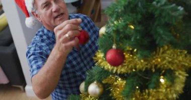 Noel Baba şapkası takıp Noel ağacı süsleyen Kafkasyalı son sınıf öğrencisinin animasyonu. Noel, şenlik ve evde gelenek.