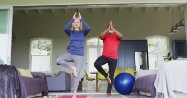 Karışık ırk son sınıf çifti evde yoga yapıyor. emeklilik ve aktif yaşlı yaşam tarzı konsepti