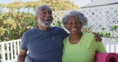 Mutlu Afro-Amerikan son sınıf çifti verandada yoga minderleri tutuyor. aktif ve sağlıklı emeklilik yaşam tarzı ev ve bahçe.
