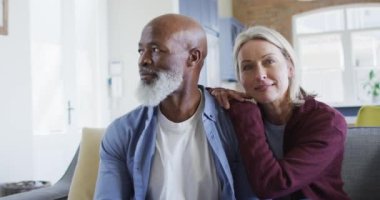 Oturma odasında oturan, kucaklayan ve gülümseyen mutlu yaşlı çift portresi. emeklilik yaşam tarzı, evde zaman geçirme..