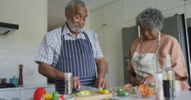 Mutlu Afro-Amerikan son sınıf çifti birlikte yemek pişirip sohbet ediyor. sağlıklı, aktif emeklilik yaşam tarzı evde.