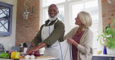 Kafkasyalı son sınıf öğrencisi kadın evdeki mutfakta kocasına önlük bağlıyor. emekli çift yaşam tarzı konsepti