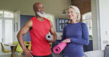 Evde yoga minderleri tutan ve gülümseyen yaşlı çiftlerin portresi. emeklilik ve aktif yaşlı yaşam tarzı konsepti