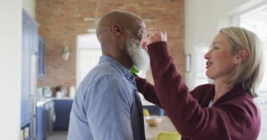 Oturma odasında kucaklaşan ve ellerinde çiçekler olan mutlu kıdemli çift. emeklilik yaşam tarzı, evde zaman geçirme..