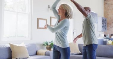 Karışık ırk son sınıf çifti evdeki oturma odasında dans ediyor. emekli çift yaşam tarzı konsepti