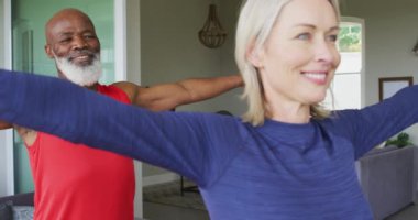 Karışık ırk son sınıf çifti evde esneme egzersizi yapıyor. emeklilik ve aktif yaşlı yaşam tarzı konsepti