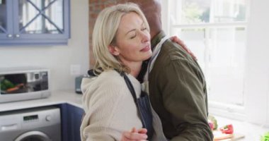 Evdeki mutfakta önlük giyip dans eden son sınıf melez bir çift. emekli çift yaşam tarzı konsepti