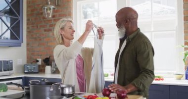 Beyaz, son sınıf öğrencisi kadın evdeki mutfakta kocasına karşı önlük giyiyor. emekli çift yaşam tarzı konsepti
