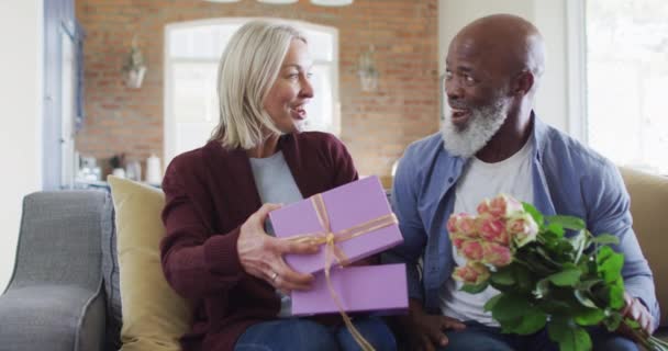 Szczęśliwa Para Seniorów Salonie Siedzi Kanapie Dając Kwiaty Prezent Emerytury — Wideo stockowe