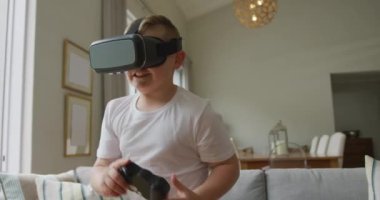 Oturma odasında duran ve evde vr kulaklık kullanan gülümseyen beyaz çocuk. Evde yalnız zaman geçirmek..