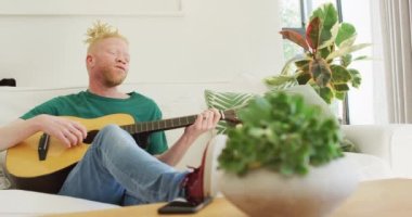 Albino Afro-Afrikalı Amerikalı. Rasta çalan, gitar çalan ve şarkı söyleyen. Boş zaman, evde dinlenme..