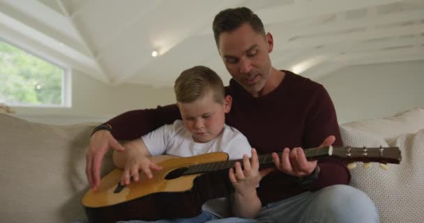 息子と一緒にギターを演奏し リビングルームに座って白人の父親 家族が家で過ごす時間 — ストック動画