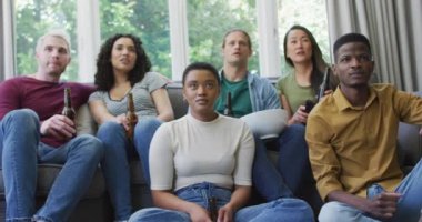 Çeşitli gençler ellerinde bira tutarak evde televizyon izlerken tezahürat yapıyorlar. spor ve eğlence konsepti