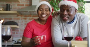 Noel 'de Noel Baba şapkalı mutlu Afrika kökenli Amerikalı çift. Noel, şenlik ve iletişim teknolojisi.