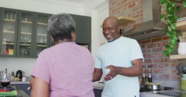 Mutlu Afro-Amerikan son sınıf çifti mutfakta dans ediyor. emeklilik yaşam tarzı dinlenme ve evde zaman geçirme.