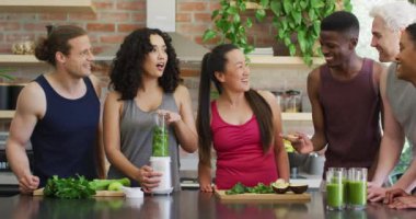 Çeşitli gençlerden oluşan bir grup evde birlikte sağlıklı yeşil meyve püresi yapıyorlar. sağlıklı yaşam tarzı ve beslenme konsepti