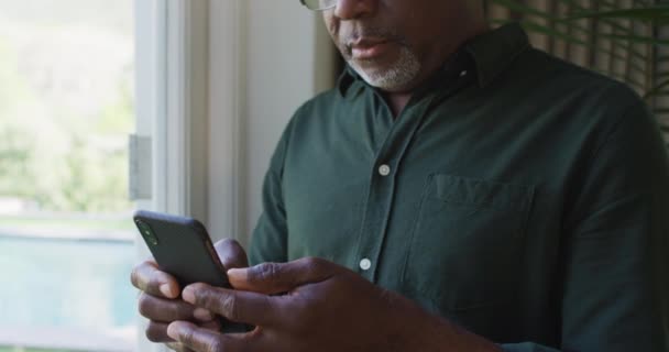 Afro Americano Homem Sênior Usando Smartphone Perto Janela Casa Aposentadoria — Vídeo de Stock