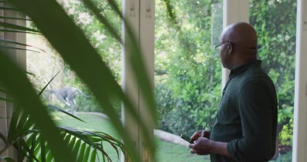 Afroamerykanin Senior Korzystający Smartfona Patrząc Przez Okno Domu Emerytura Starszy — Wideo stockowe