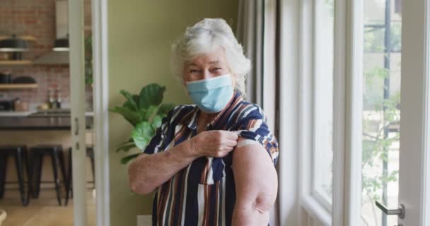 Blanke Oudere Vrouw Met Gezichtsmasker Die Haar Gevaccineerde Schouder Thuis — Stockvideo