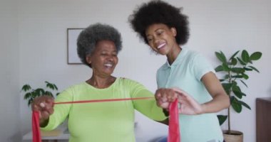 Mutlu Afro-Amerikan kadın fizyoterapist yaşlı kadın hastaların evde egzersiz yapmasına yardım ediyor. Üst düzey sağlık ve tıbbi fizyoterapi tedavisi.