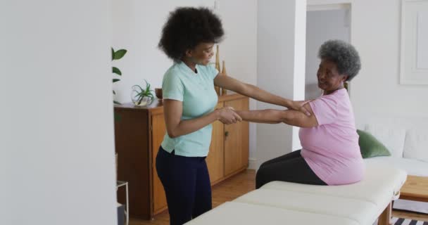 Fisioterapeuta Afro Americana Usando Máscara Facial Ajudando Paciente Idosa Exercitar — Vídeo de Stock