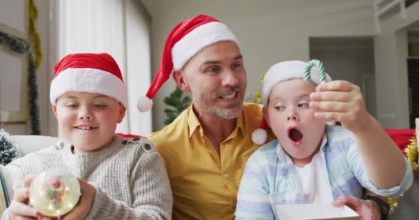 소파에 글로브와 사탕을 아버지와 아들의 크리스마스 축하와 축하의 — 비디오