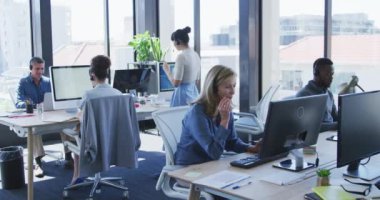 Modern bir ofiste çalışan, kulaklık takan, konuşan, ağır çekimde çalışan çeşitli iş adamlarının ön görüşü.