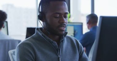 Modern bir ofiste çalışan, kulaklık takan, konuşan, yavaş çekim yapan melez bir işadamının ön görüşü.