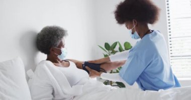 Afrika kökenli Amerikalı kadın doktor ve maskeli yaşlı kadın hasta. covid 19 salgını sırasında üst düzey sağlık, destek ve yaşam tarzı.