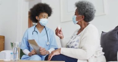 Afrika kökenli Amerikalı kadın doktor ve maskeli yaşlı kadın hasta. covid 19 salgını sırasında üst düzey sağlık, destek ve yaşam tarzı.