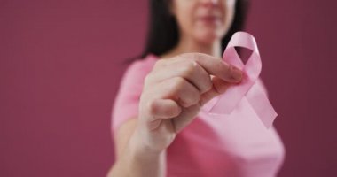 Pembe arka planda pembe kurdele tutan bir kadının orta bölümü. Göğüs kanseri farkındalığı kavramı