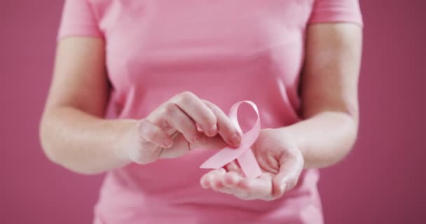 ピンクの背景にピンクのリボンをつけた女性のミッドセクション 乳がんの認知概念は — ストック動画