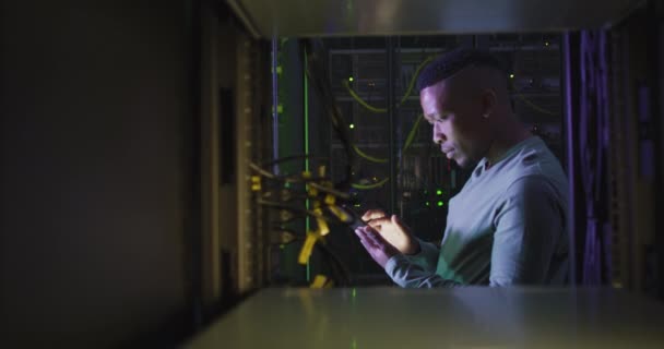 非裔美国男性计算机技师使用智能手机在商业服务器室工作 数字信息存储和通信网络技术 — 图库视频影像