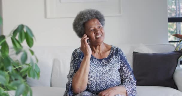 非洲裔美国老年妇女坐在沙发上 使用智能手机 退休后的生活方式随着科技的进步而放松 — 图库视频影像