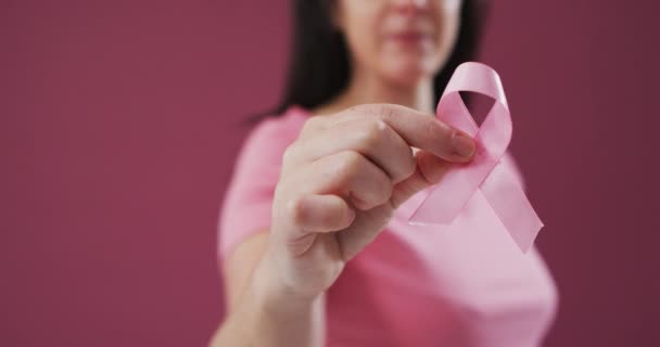 中间部分的女人拿着粉红色的带与粉红色的背景 乳腺癌意识概念 — 图库视频影像