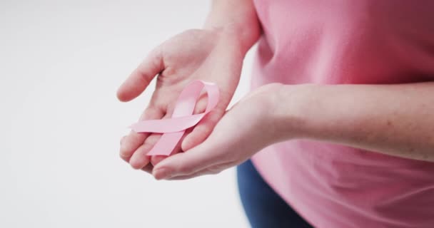 白を背景にピンクのリボンを持つ女性のミッドセクション 乳がんの認知概念は — ストック動画