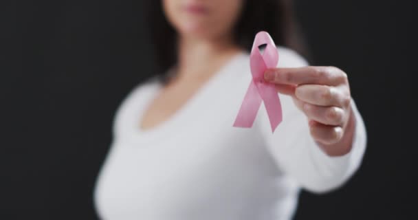 黒を背景にピンクのリボンを持つ女性のミッドセクション 乳がんの認知概念は — ストック動画