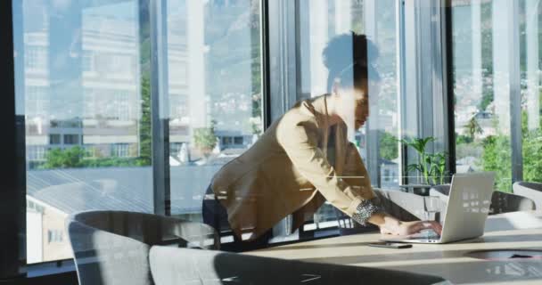 窓を通して見られるラップトップコンピュータを使用して現代のオフィスで働く混合レースビジネス女性の側面図 スローモーション — ストック動画