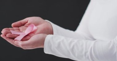 Siyah arka planda pembe kurdele tutan bir kadının orta bölümü. Göğüs kanseri farkındalığı kavramı
